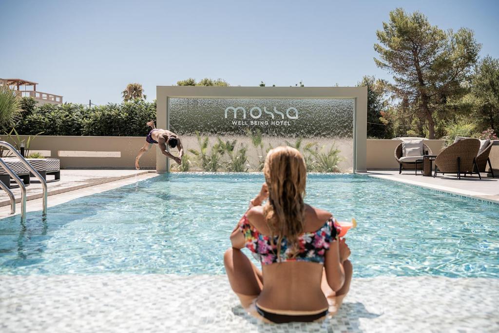una mujer en bikini sentada en una piscina en Mossa Well Being Hotel en Kato Daratso