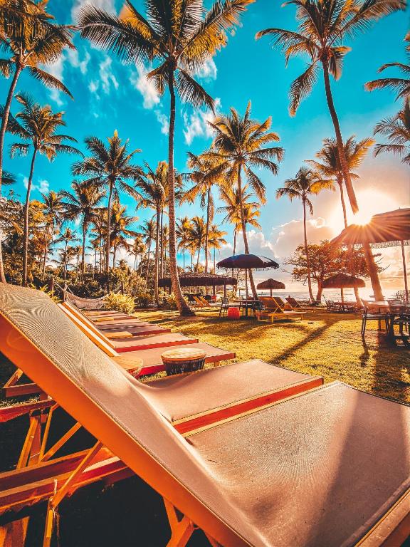 a row of hammocks on a beach with palm trees at Maion Hotel e Boutique in Praia do Espelho
