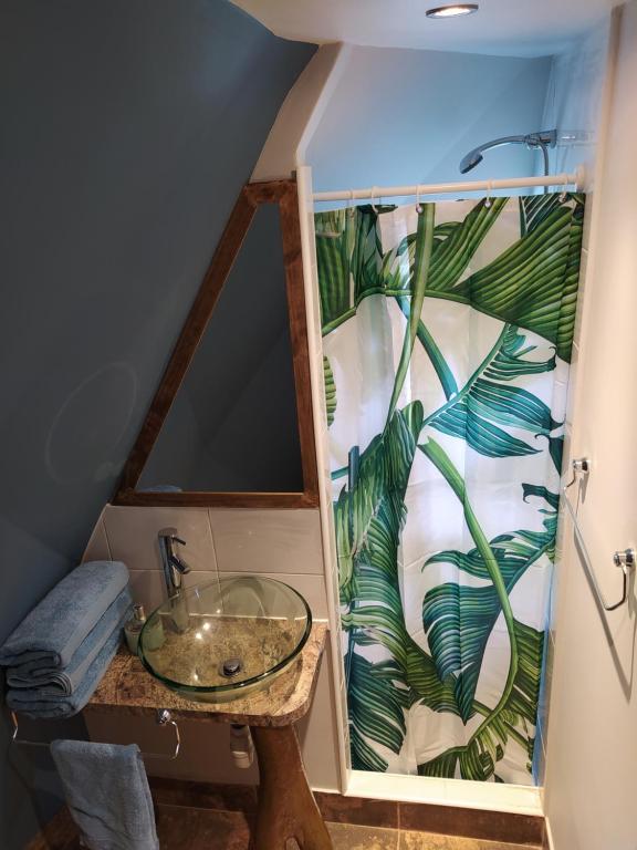 baño con lavabo de cristal y mural de una planta en Casa Pumahue, en La Ensenada