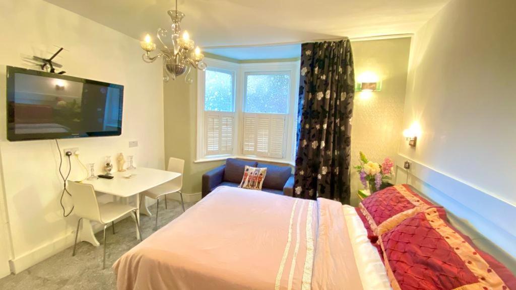 a bedroom with a bed and a table and a tv at Modern and cosy studio flat in London