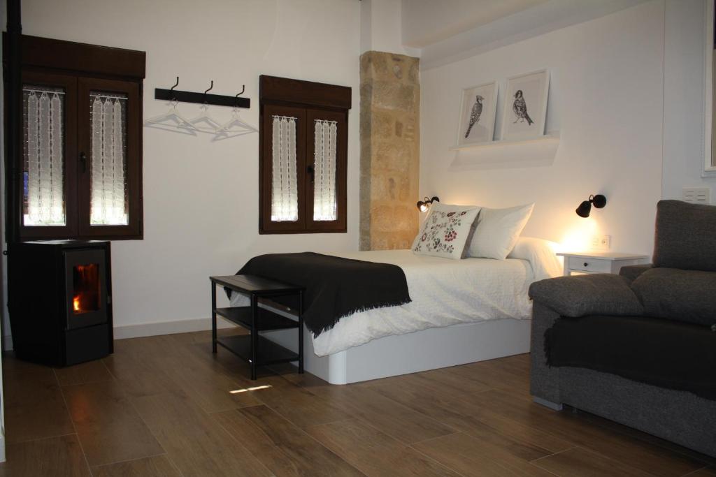 a white bedroom with a bed and a couch at Barbacana, dieciocho in Baeza