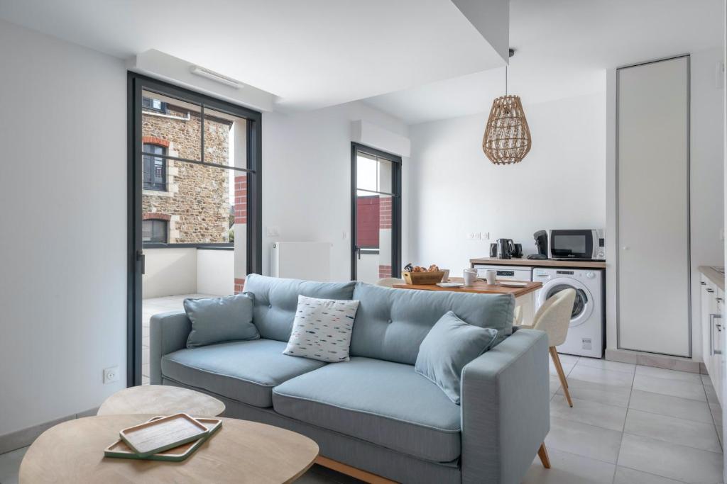 プレヌフ・ヴァル・アンドレにある50m de la plage, bel appartement pour 4の青いソファとテーブルのあるリビングルーム