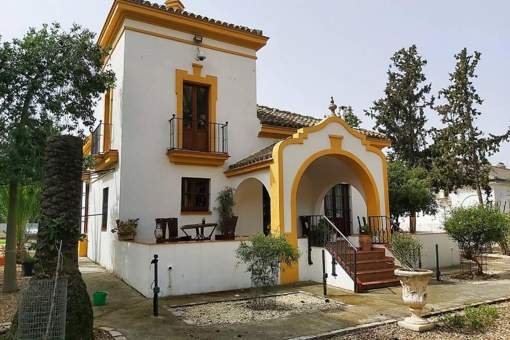 a white and yellow house with a porch and stairs at Cortijo San José in Seville