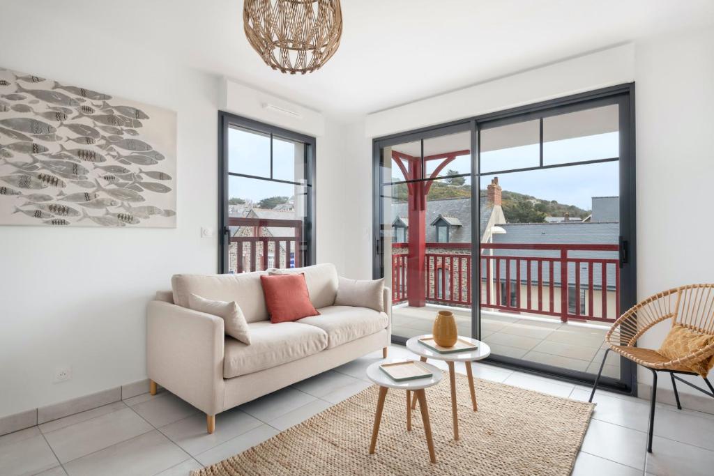 Una sala de estar con un sofá y un balcón. en Bel appartement pour 4 à 50m de la plage, en Pléneuf-Val-André