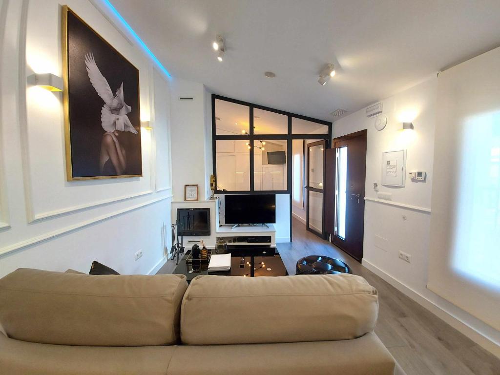 a living room with a couch and a tv at Casa Casiopea Elegante y exótica in Sanlúcar de Guadiana