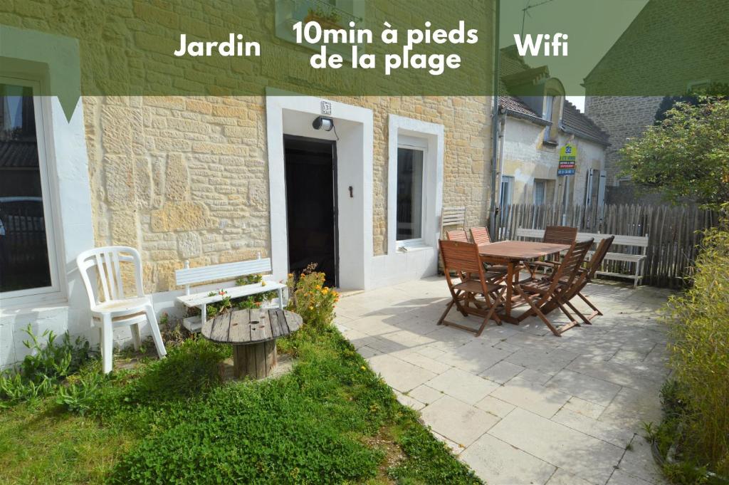 een patio met een tafel en stoelen en een gebouw bij Maison de charme bord de mer - Avec jardin et wifi in Luc-sur-Mer