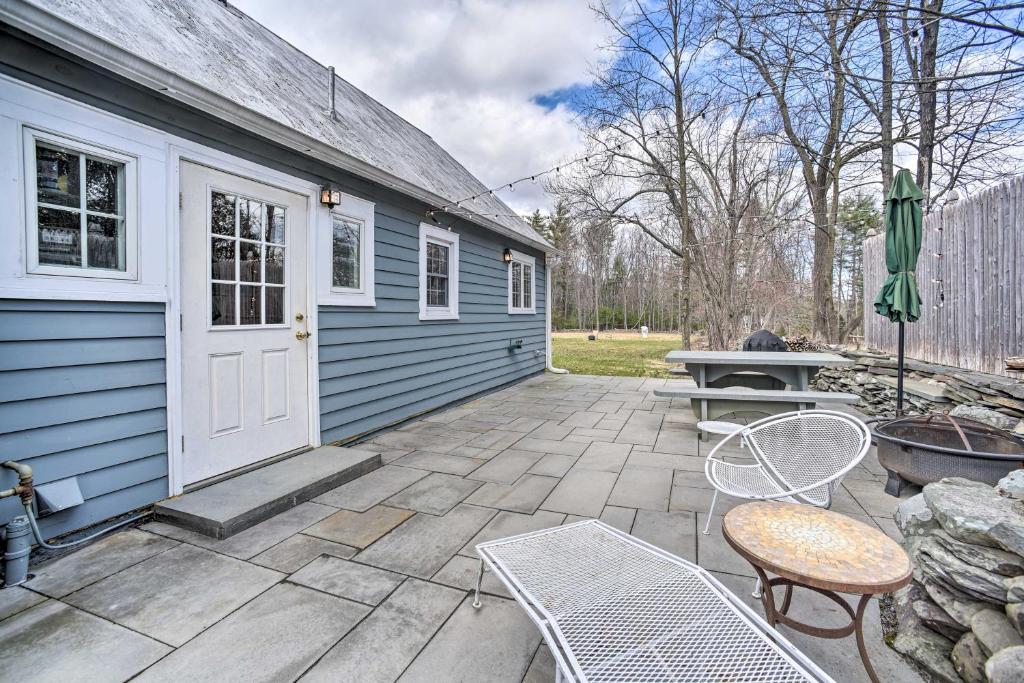 a patio with a blue house and a table and chairs at Charming Cottage with Yard - 2 Mi to Tinker St! in Woodstock