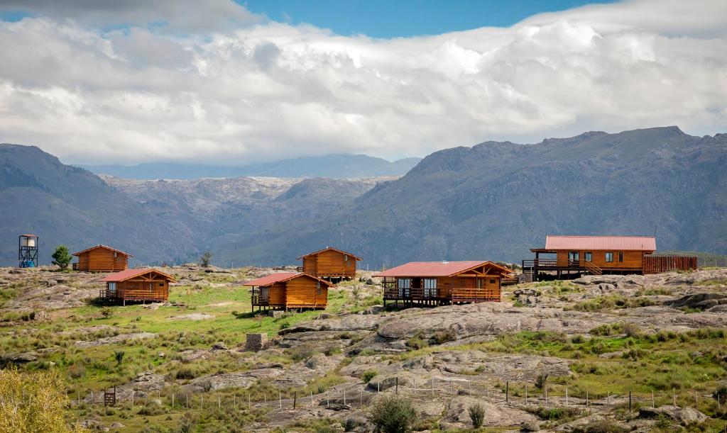 um grupo de casas numa colina com montanhas em Alma Serrana - Suites de montaña! em La Cumbrecita