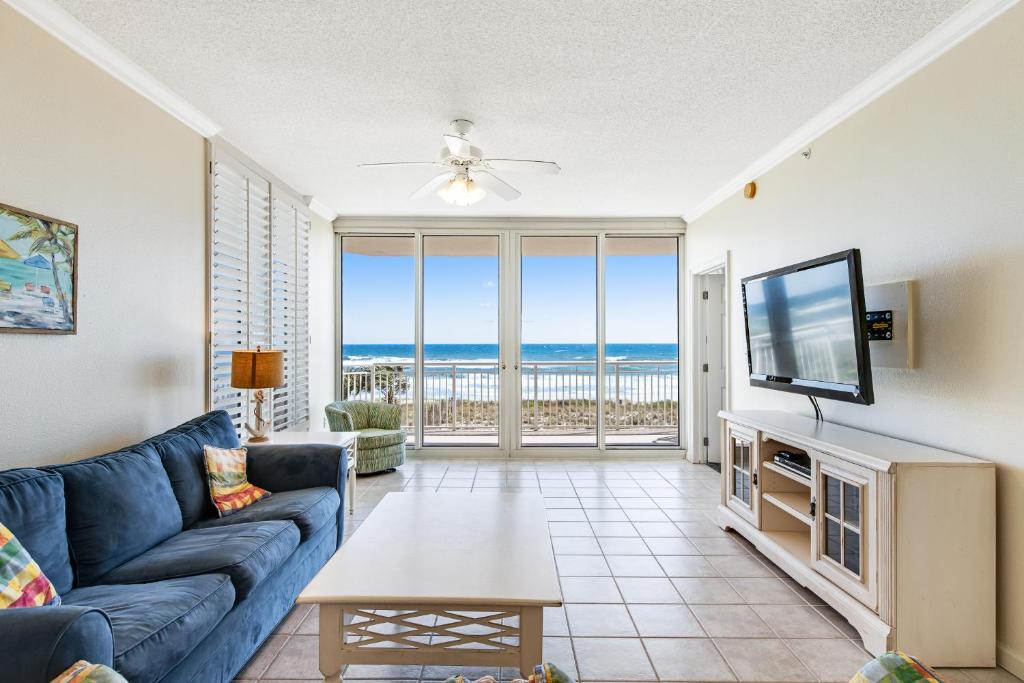 a living room with a blue couch and a tv at Pearl Condos in Navarre