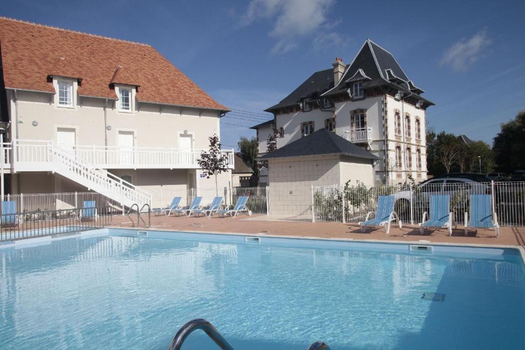 una grande piscina di fronte a un edificio di Résidence Odalys Le Domaine des Dunettes a Cabourg