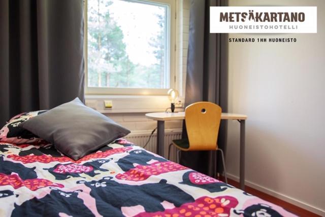 a bedroom with a bed and a table and a window at Metsäkartano in Kannus