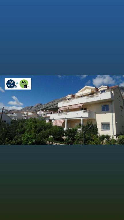 a large white building with trees in front of it at Apartmani Villa Marija in Omiš
