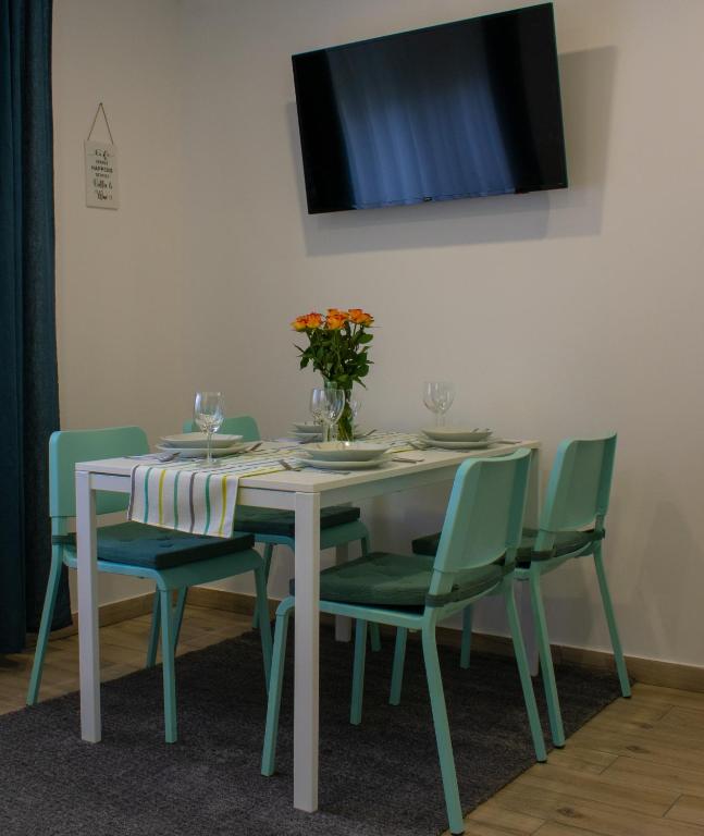 einen Esstisch mit grünen Stühlen und einen TV in der Unterkunft Apartman i studio apartman Vitana in Garešnica