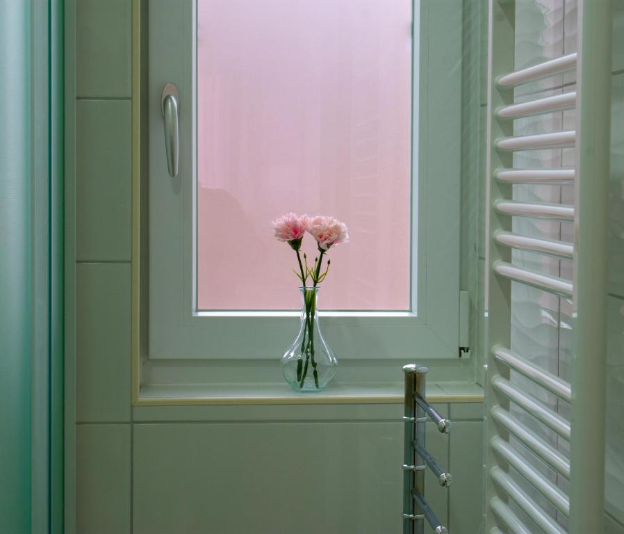 eine Vase mit rosa Blumen auf einem Fensterbrett in der Unterkunft Apartman i studio apartman Vitana in Garešnica