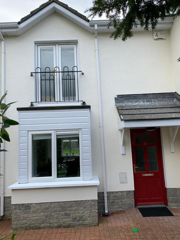 a white house with a red door and a balcony at Two Bedroom Town House Beside The River Barrow in Carlow