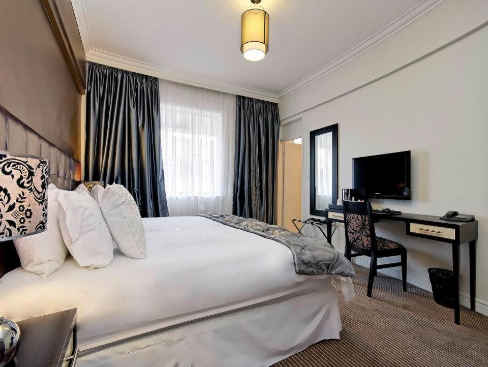 a hotel room with a large bed and a desk at Ascot Hotel in Johannesburg