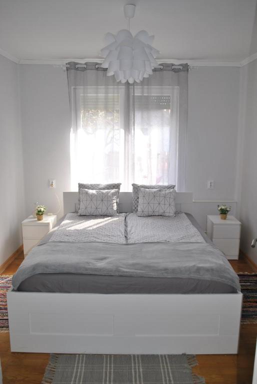 uma grande cama branca num quarto branco com um lustre em Rózsa Vendégház em Abádszalók