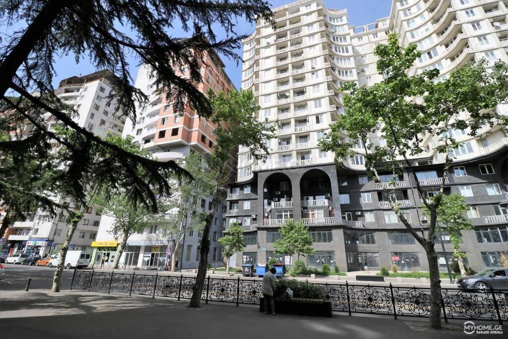 Un uomo in piedi di fronte a un palazzo con edifici alti di Niko's Apartments on Shartava Street a Tbilisi City