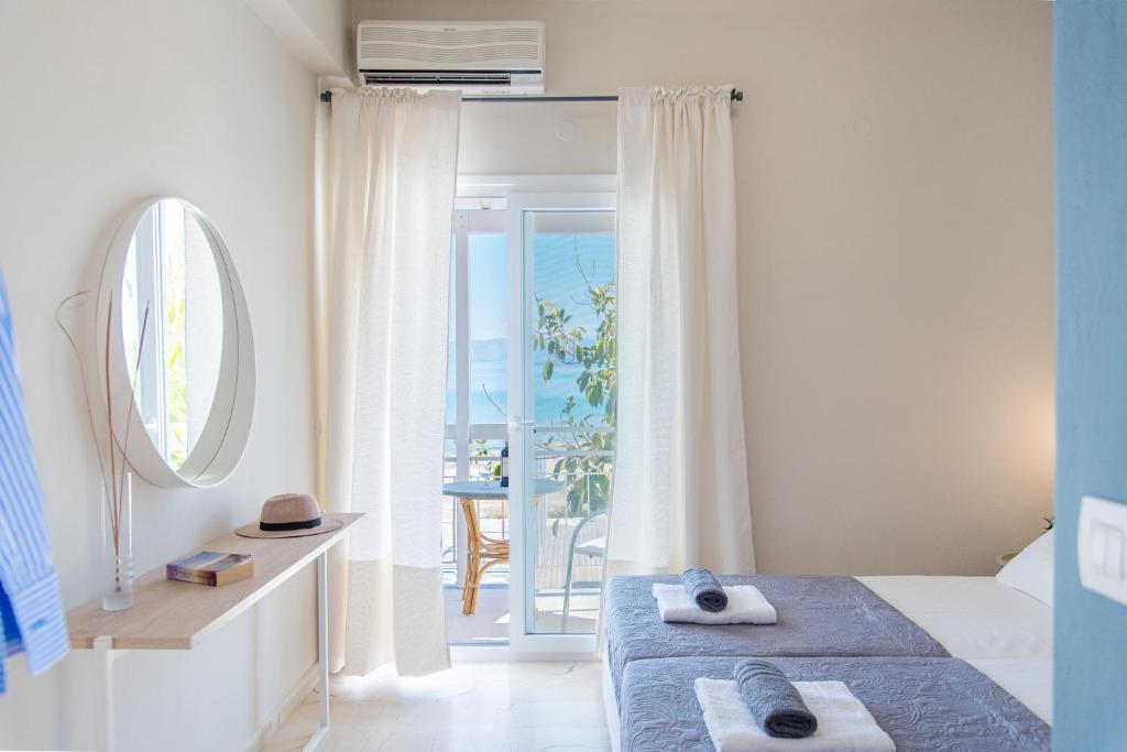 een slaapkamer met een bed en een spiegel en een balkon bij Ammos Apartments in Kavos