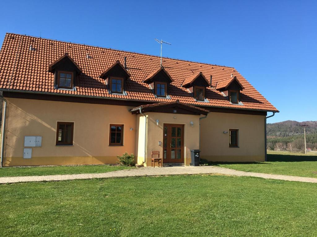 una casa con tetto rosso e un prato di Pension Hofberg a Jetřichovice