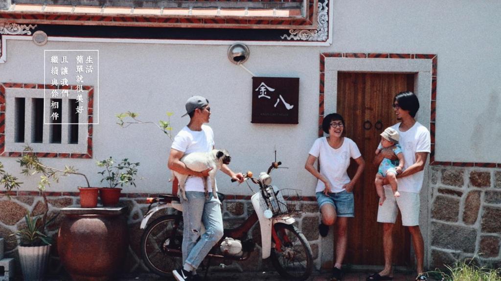 Kinba Guest House في Jinning: مجموعة من الناس تقف خارج منزل مع دراجة نارية