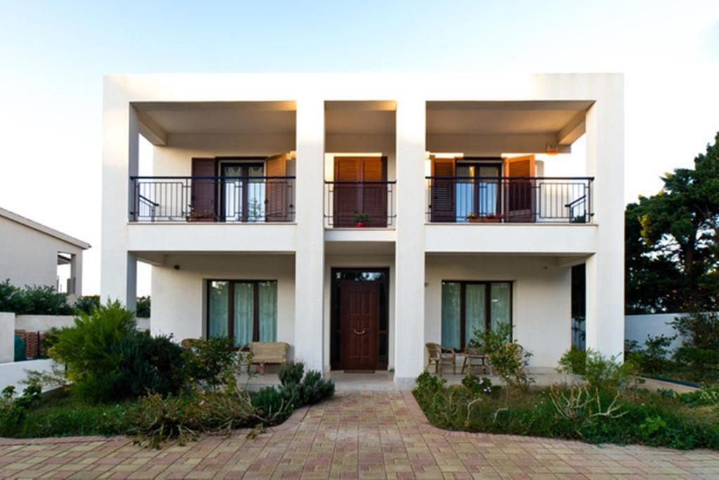 a white building with balconies and a door at Open Space San Cusumano in Erice