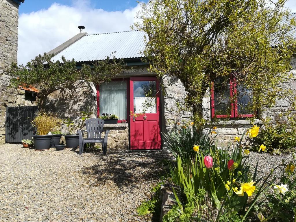 a stone cottage with a red door and flowers at Druid cottage in Glendree