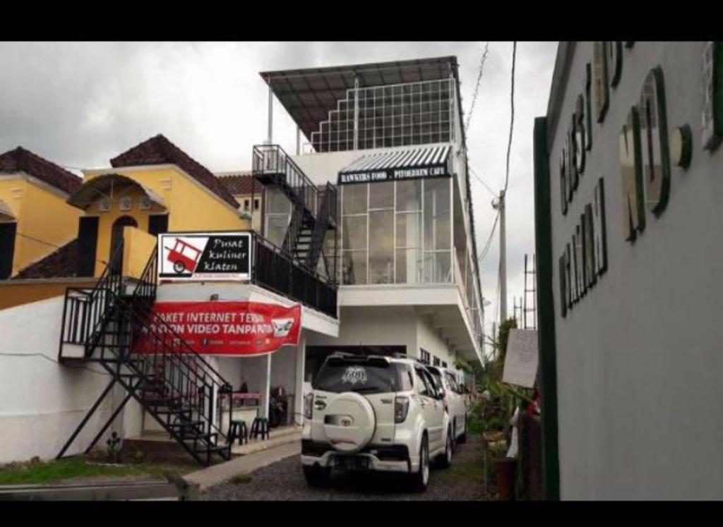 uma carrinha branca estacionada em frente a um edifício em D'SAWAH GUESTHOUSE em Klaten