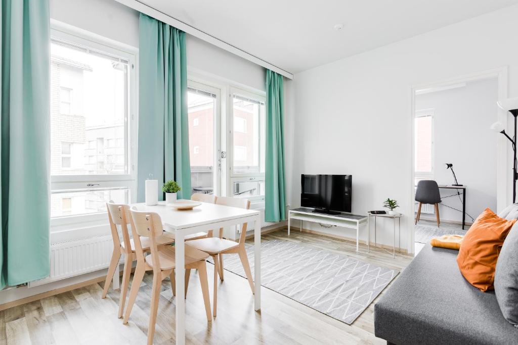 uma sala de estar com uma mesa e um sofá em Hiisi Homes Tampere Armonkallio em Tampere