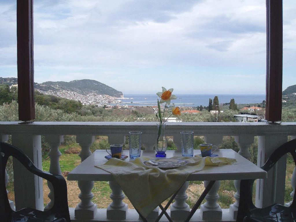 una mesa con un jarrón de flores en el balcón en Alexandros Rooms & Studios en Skopelos Town