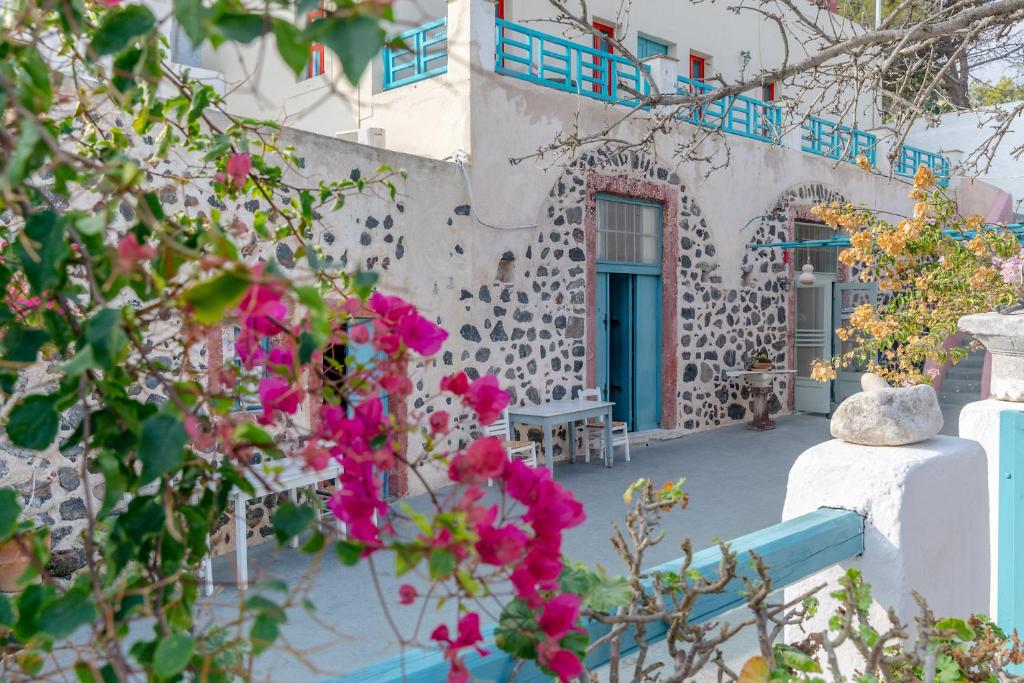 un edificio con una puerta azul y flores rosas en Caveland en Karterados