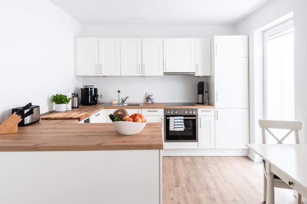 a kitchen with white cabinets and a bowl of fruit on the counter at Schöner wohnen im Herzen Oldenburgs in Oldenburg