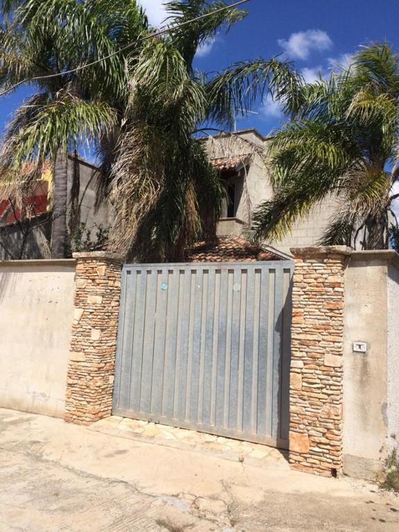 um portão para uma casa com uma palmeira atrás dela em villa domenica em Torre Squillace