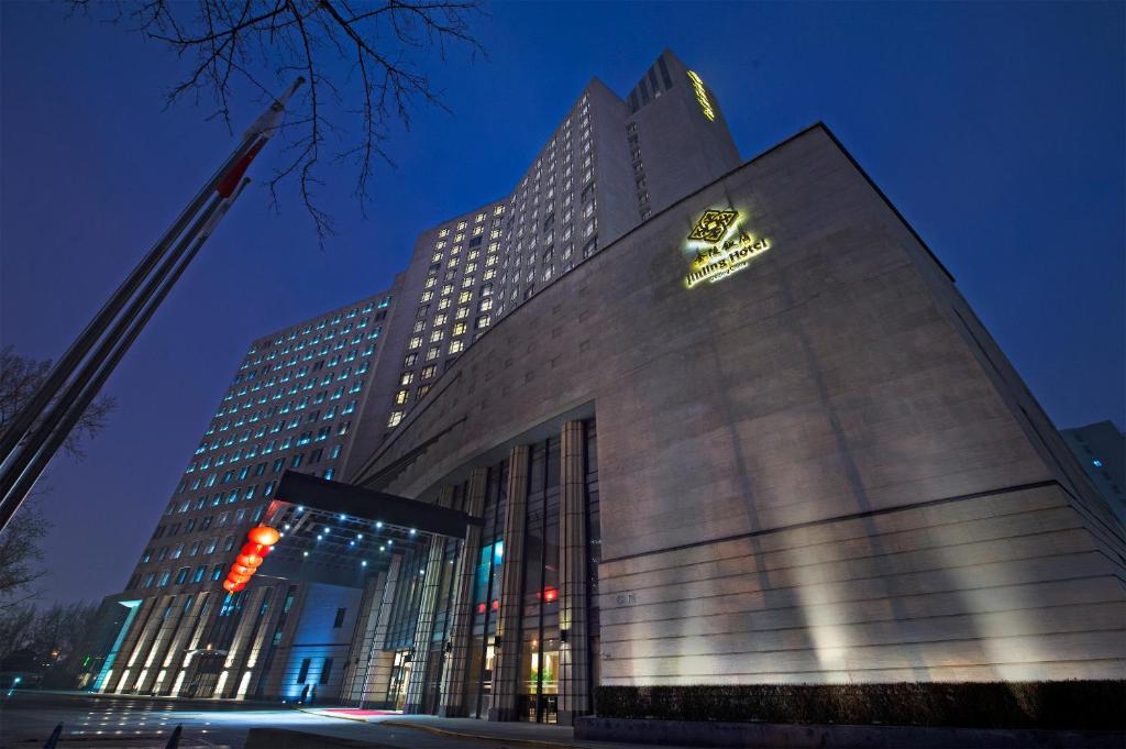 een hoog gebouw met 's nachts een bord bij Jinling Hotel Beijing in Beijing