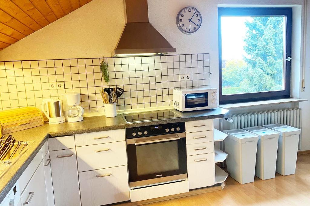 een keuken met witte kasten, een magnetron en een raam bij Ferienwohnung in Laichingen-Feldstetten in Laichingen