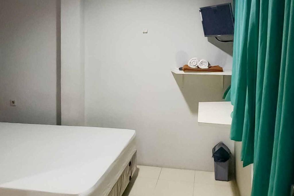 ein weißes Zimmer mit einem Bett und einem grünen Vorhang in der Unterkunft Rumahku Hayam Wuruk Mitra RedDoorz in Jakarta