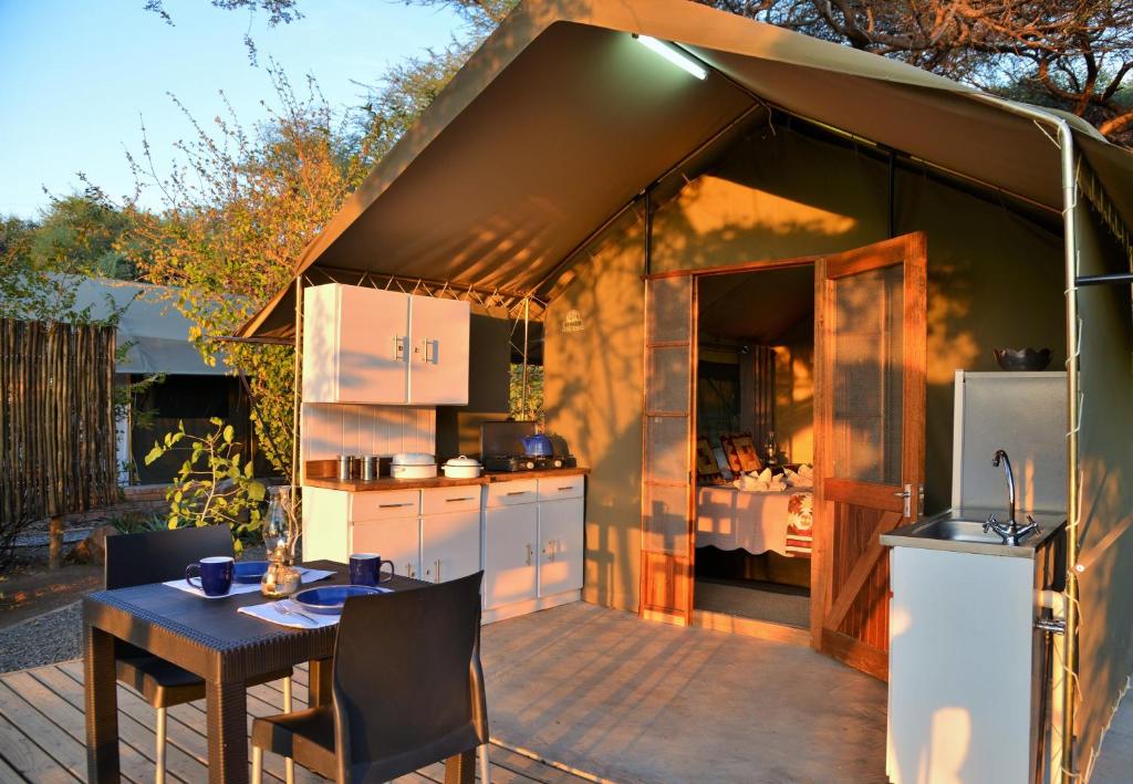 uma cozinha numa tenda com uma mesa e cadeiras em Muchenje self-catering Tents em Chobe