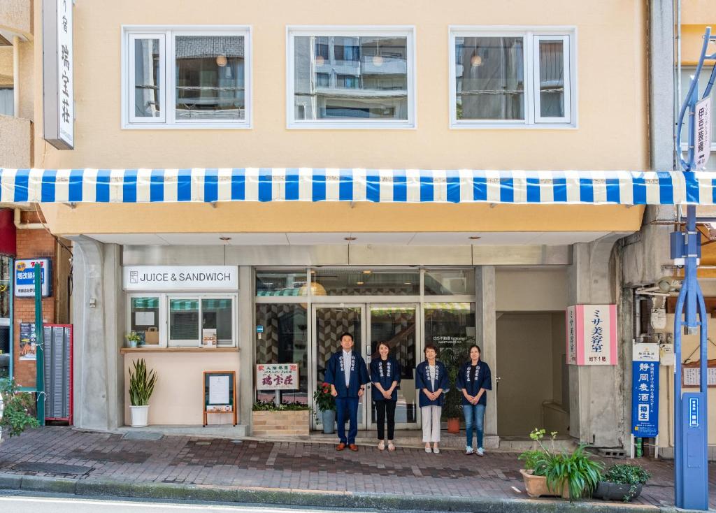 eine Gruppe von Personen, die vor einem Gebäude stehen in der Unterkunft 素泊まり宿　瑞宝荘 in Atami