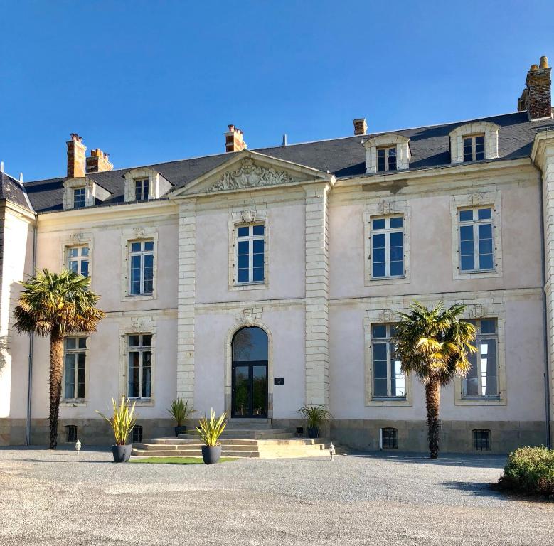 a large white house with palm trees in front of it at Hôtel Particulier CHÂTEAU DES MARAIS Proximité et vue sur le Lac de Grand lieu in Saint-Philbert-de-Grand-Lieu