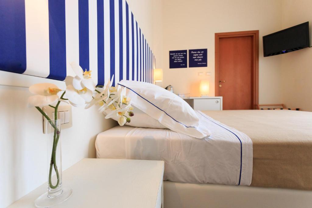 um quarto com uma cama e um vaso de flores sobre uma mesa em Mini Hotel em Rimini