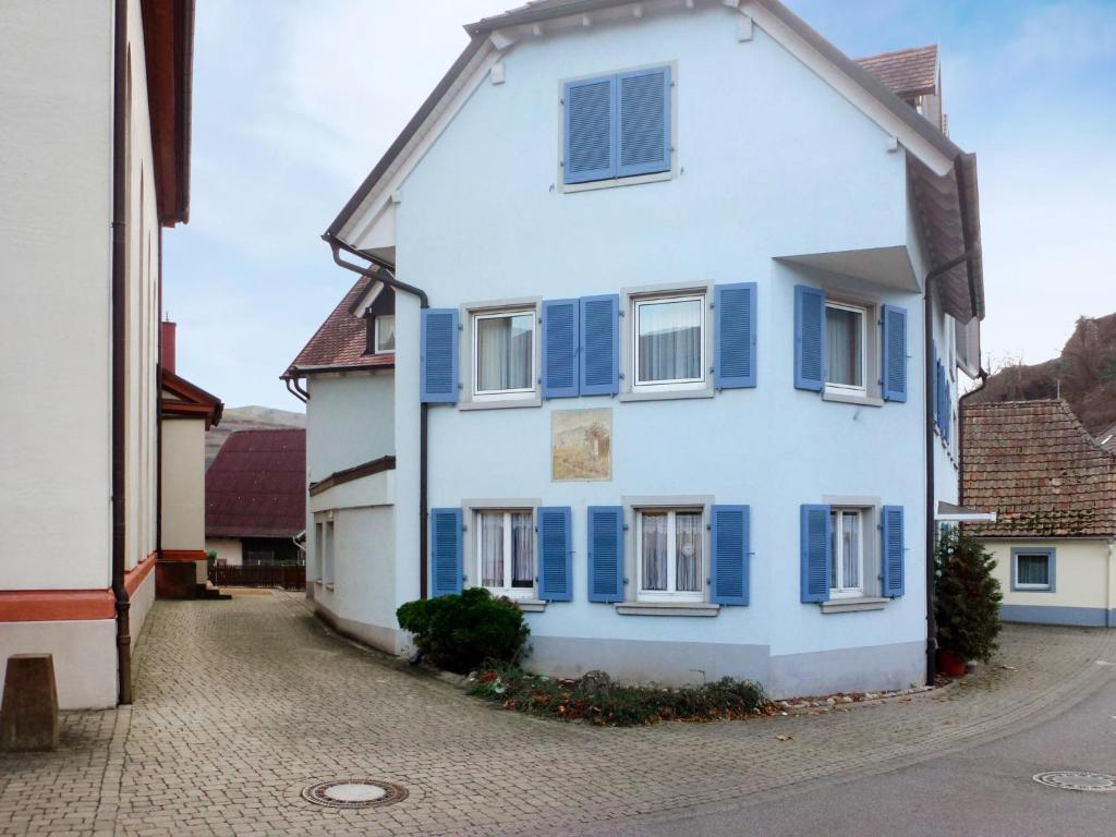 una casa blanca con persianas azules en una calle en Apartment Flesch-2 by Interhome, en Schelingen