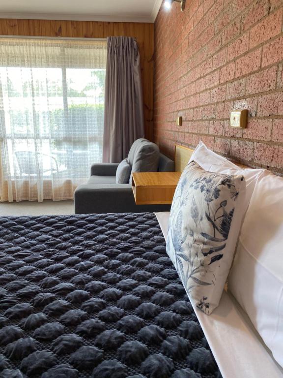 Un dormitorio con una cama y una pared de ladrillo. en Country Roads, en Peak Hill