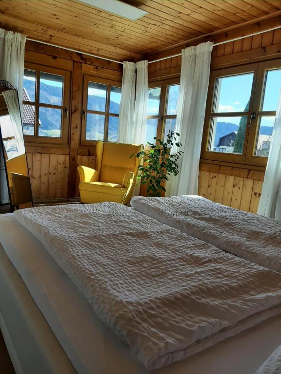um quarto com uma cama, uma cadeira e janelas em Ferienwohnung "Marie's Auszeit" em Bodensdorf