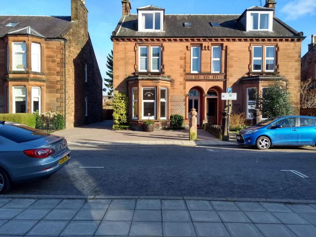 a blue car parked in front of a house at Lindean Guest House in Dumfries