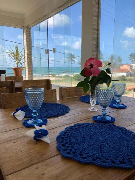 a table with blue glasses and a vase of flowers on it at Pousada A Casa Portuguesa in Cabo de Santo Agostinho