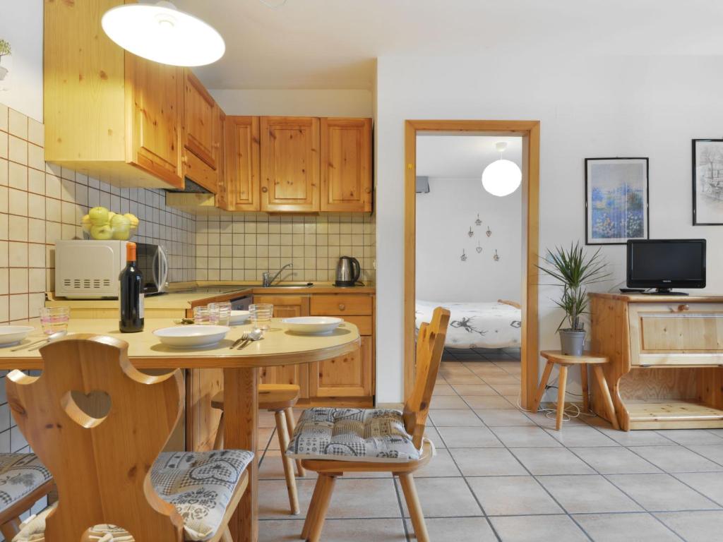 eine Küche mit Holzschränken sowie einem Tisch und Stühlen in der Unterkunft Apartment Cesa Manzini-2 by Interhome in Canazei