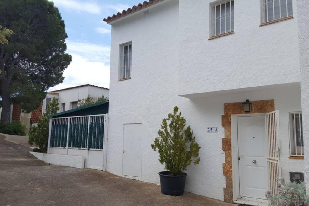 een wit huis met een witte deur en een potplant bij Casa Almadrava in Roses
