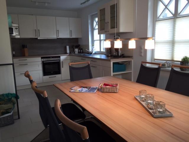 a kitchen with a wooden table with chairs around it at Lindenstr_ _Lille Hus 1_ in Zingst