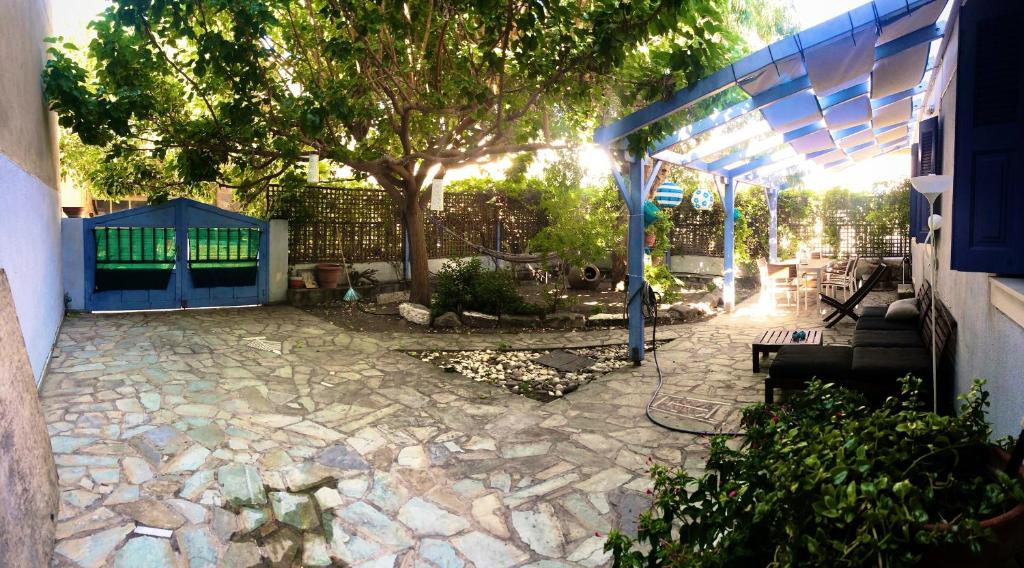 un patio con un árbol y una valla azul en Blue Seaside House with Garden, en Skala Eresou