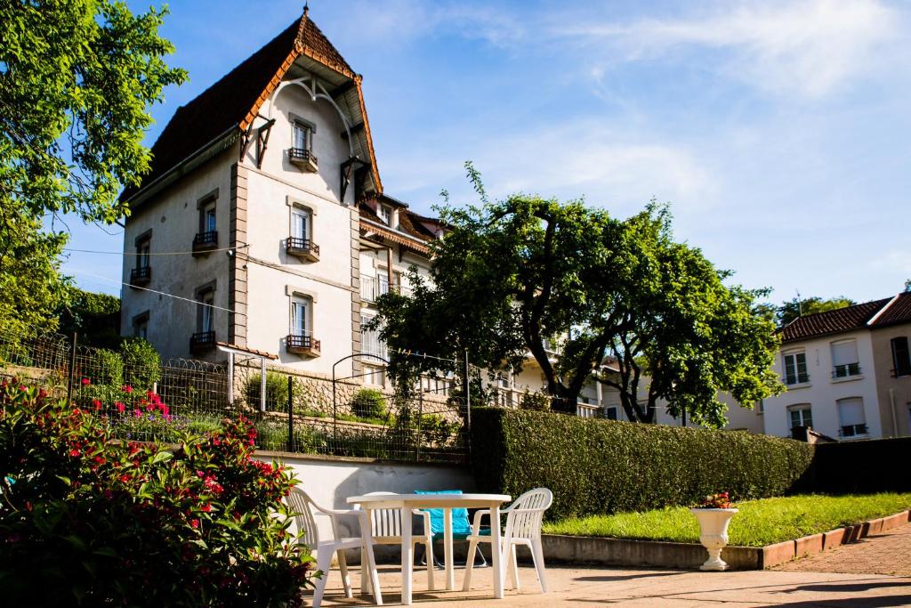 een tafel en stoelen voor een gebouw bij Pension Gérard in Bourbonne-les-Bains